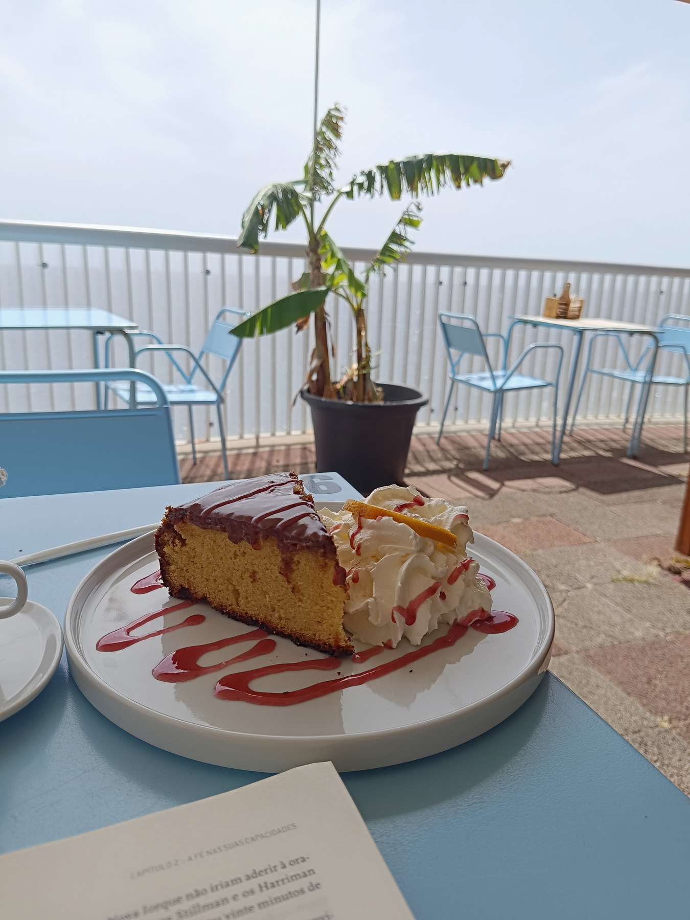 Cake and cream on a blue café table on a seaside terrace